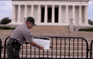 a National Park Service guard puts up a closed sign in front of the Lincoln Memorial, reading "because of the federal government shutdown all national parks are closed."