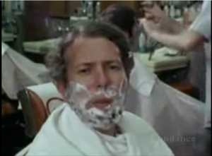 Dr. Milgram, a middle-aged white professor with poofy hair, demonstrating social contexts, with shaving cream on his face